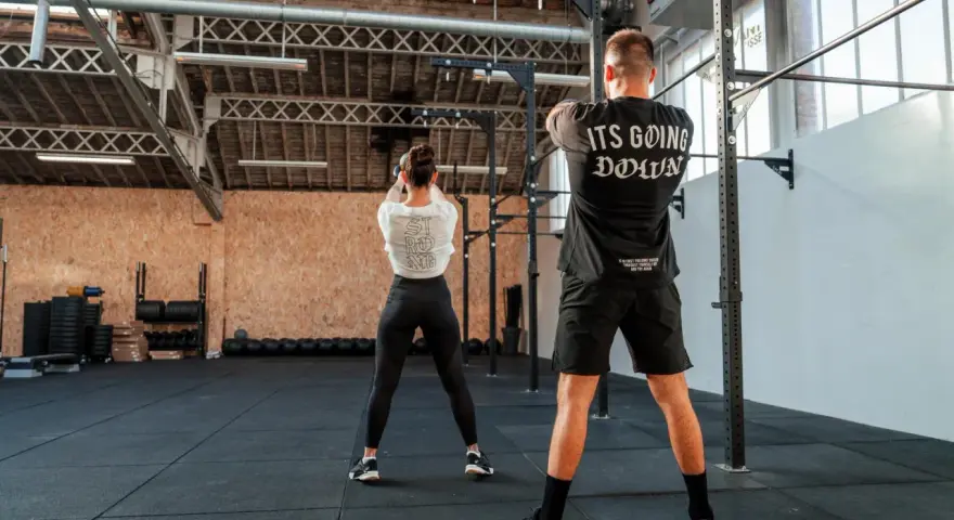 Para ćwicząca z kettlebell w siłowni CrossFit.